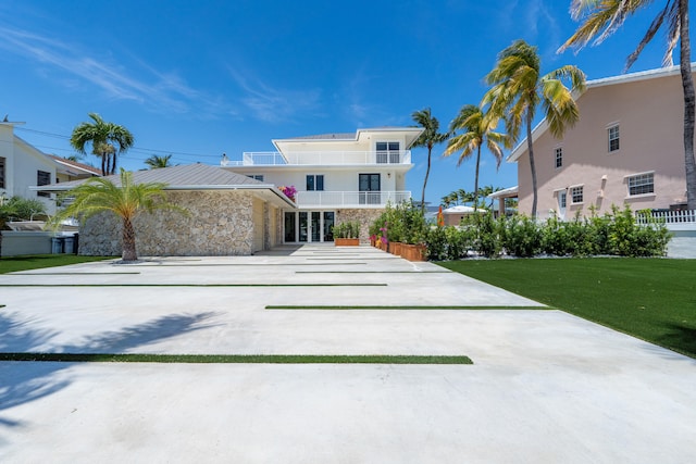 view of front facade with french doors, a balcony, and a front lawn