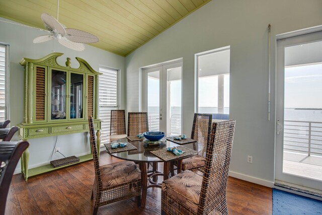 dining space featuring dark wood-type flooring, a water view, vaulted ceiling, wooden ceiling, and french doors