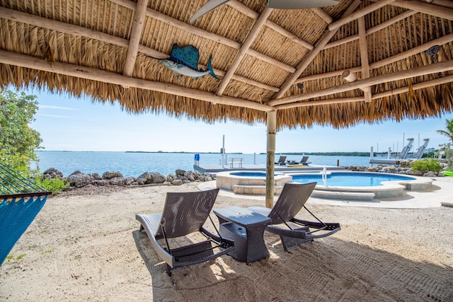 view of patio with a gazebo, a water view, and a swimming pool with hot tub