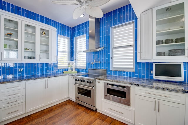 kitchen featuring wall chimney range hood, appliances with stainless steel finishes, backsplash, dark hardwood / wood-style floors, and white cabinets