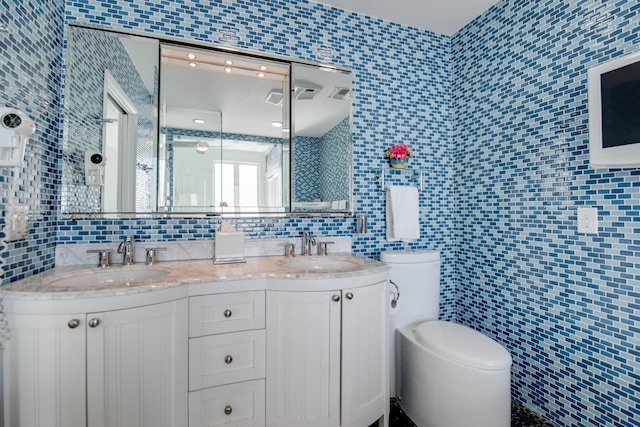 bathroom featuring vanity, toilet, and tile walls