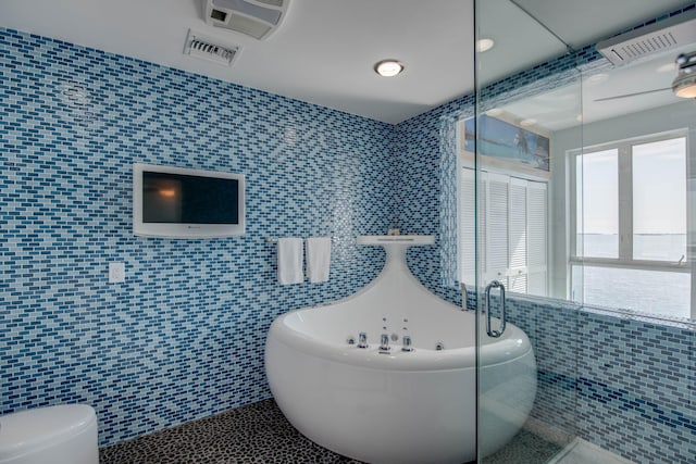 bathroom featuring tile walls, a bath, tile patterned flooring, and toilet