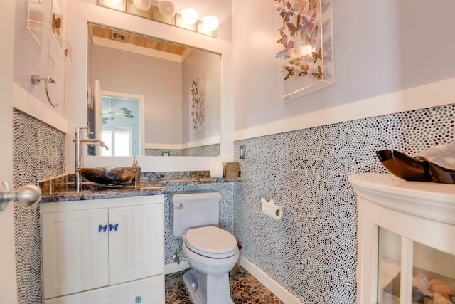 bathroom with vanity, toilet, and tile walls