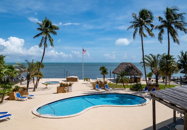 view of swimming pool featuring a community hot tub, a water view, a gazebo, and a patio area