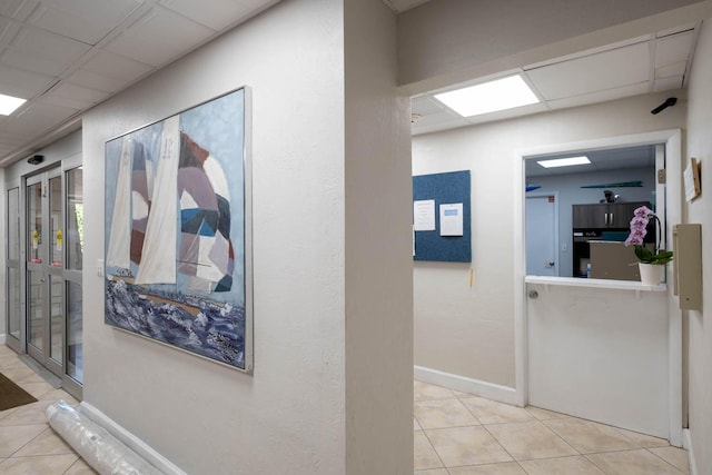 corridor featuring a drop ceiling and light tile patterned floors