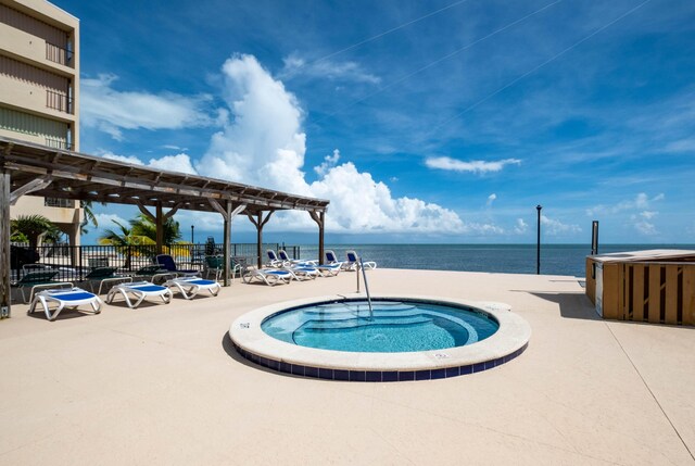 view of pool featuring a patio area, a hot tub, and a water view