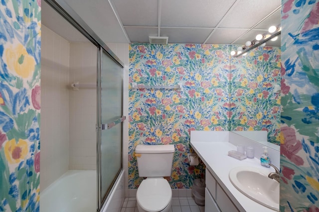 full bathroom with combined bath / shower with glass door, a paneled ceiling, tile patterned flooring, vanity, and toilet