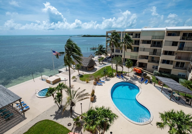 view of pool featuring a water view and a patio