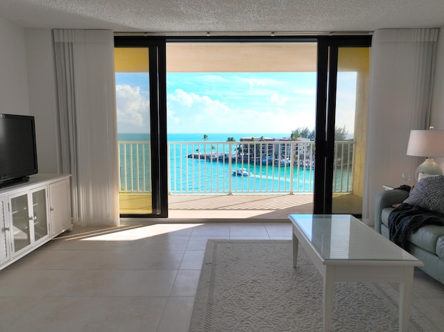 unfurnished living room featuring floor to ceiling windows, a water view, tile patterned floors, and a textured ceiling