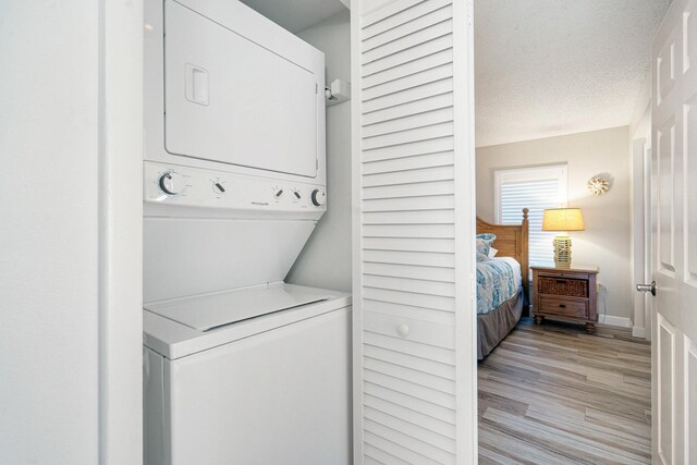500 Burton Dr Unit 1316, Tavernier, FL 33070 - laundry room with stacked washer and dryer, a textured ceiling, light wood-style flooring, laundry area, and baseboards