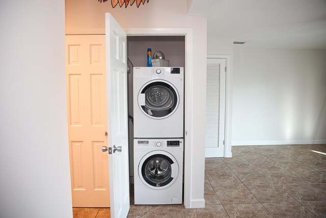 laundry room featuring stacked washer / drying machine and tile patterned floors