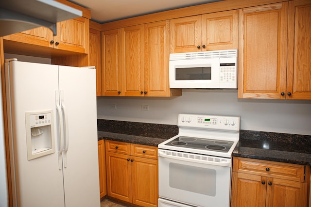 kitchen featuring dark stone countertops and white appliances