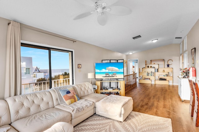 living area with lofted ceiling, a textured ceiling, visible vents, a ceiling fan, and light wood-type flooring