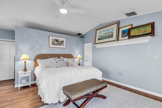 bedroom with vaulted ceiling, wood finished floors, visible vents, and baseboards