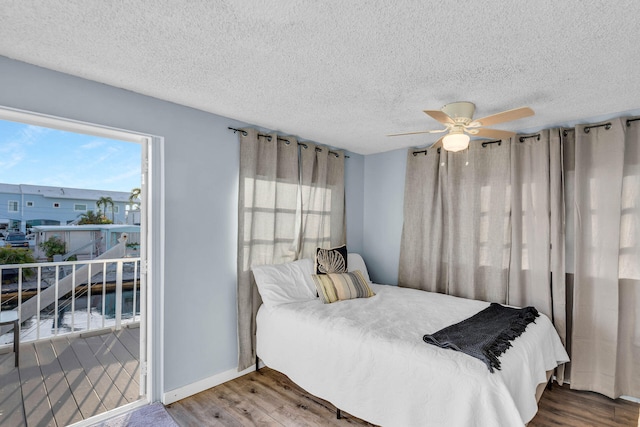 bedroom with a ceiling fan, a textured ceiling, baseboards, and wood finished floors