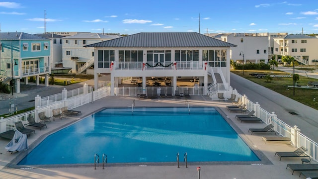 back of property featuring a community pool, a patio area, and a sunroom