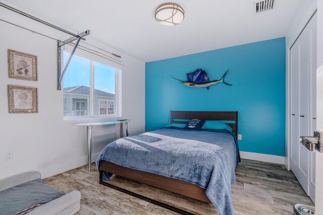 bedroom with light hardwood / wood-style floors and a closet