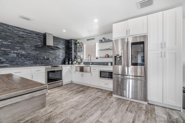 kitchen with white cabinetry, appliances with stainless steel finishes, and wall chimney range hood