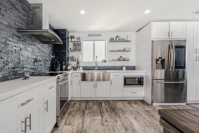 kitchen featuring white cabinets, stainless steel appliances, sink, and wall chimney range hood