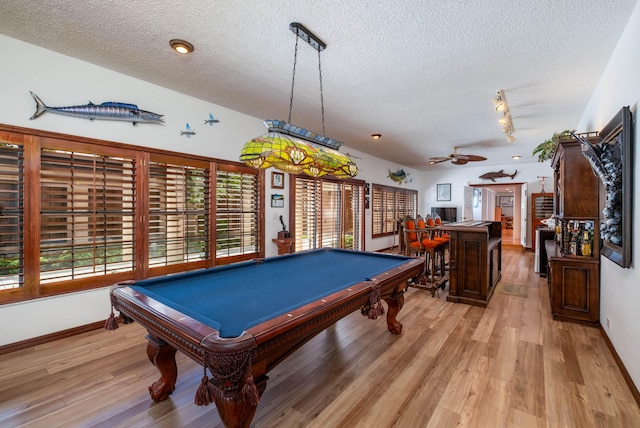 recreation room with light wood-style floors, track lighting, baseboards, and a textured ceiling