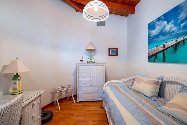 bedroom featuring visible vents, lofted ceiling with beams, wood ceiling, wood finished floors, and baseboards