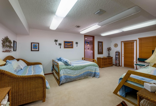 carpeted bedroom featuring a textured ceiling, washing machine and clothes dryer, and visible vents
