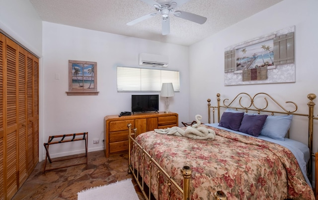bedroom with a textured ceiling, ceiling fan, baseboards, a wall mounted AC, and a closet