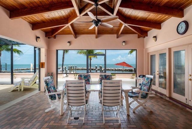 sunroom with ceiling fan, a water view, wood ceiling, french doors, and beam ceiling