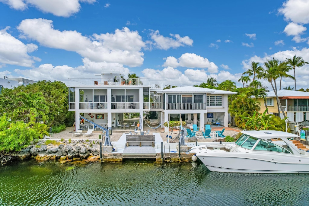 rear view of house with a water view, a patio, and a sunroom