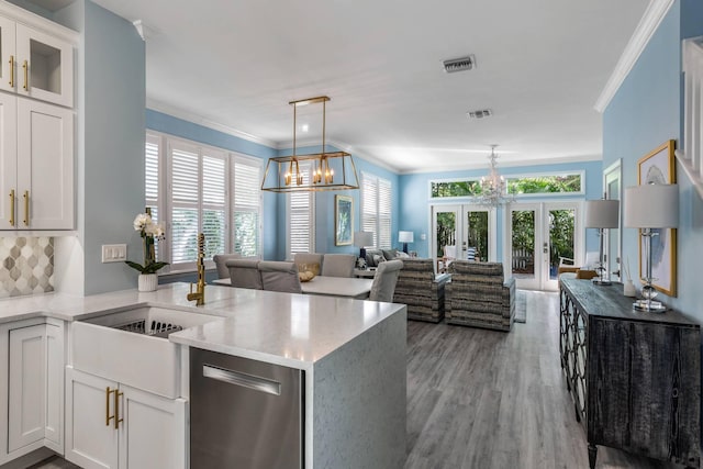 kitchen featuring french doors, decorative light fixtures, kitchen peninsula, a notable chandelier, and white cabinets