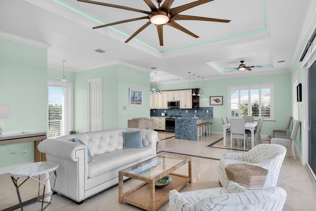 living room with ornamental molding, plenty of natural light, and a tray ceiling