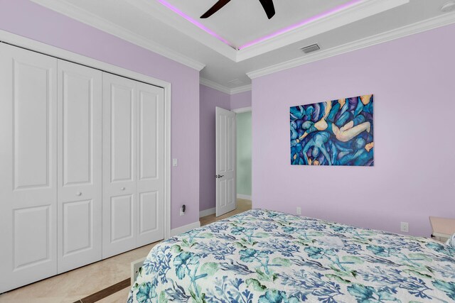 bedroom featuring ceiling fan, ornamental molding, a tray ceiling, and a closet