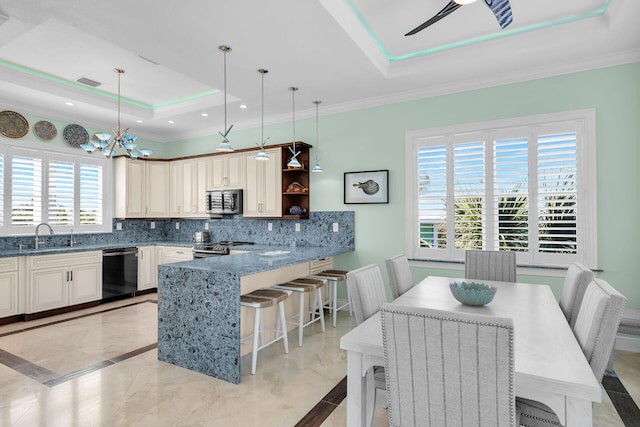 kitchen with appliances with stainless steel finishes, a raised ceiling, hanging light fixtures, and a breakfast bar area