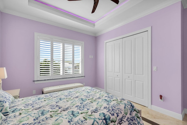 carpeted bedroom with a closet, crown molding, a raised ceiling, and ceiling fan