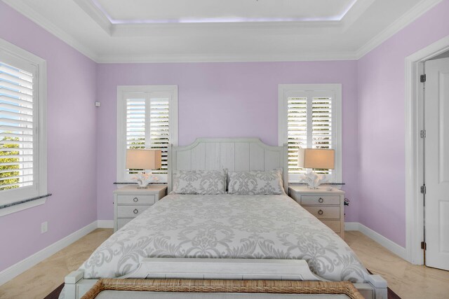 bedroom featuring ornamental molding, a tray ceiling, and multiple windows