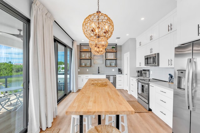 949 24th St, Ocean, Marathon, FL 33050 - kitchen with stainless steel appliances, open shelves, a chandelier, light wood-style flooring, and tasteful backsplash