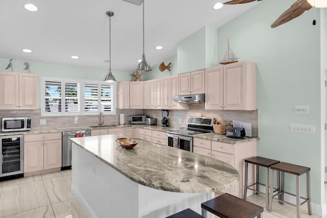 150 10th St, Key Colony, FL 33051 - kitchen featuring appliances with stainless steel finishes, beverage cooler, under cabinet range hood, backsplash, and light stone counters