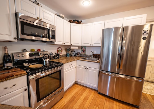 1124 Catherine St Unit 202, Key West, FL 33040 - kitchen featuring stainless steel appliances, a sink, white cabinets, and light wood-style flooring