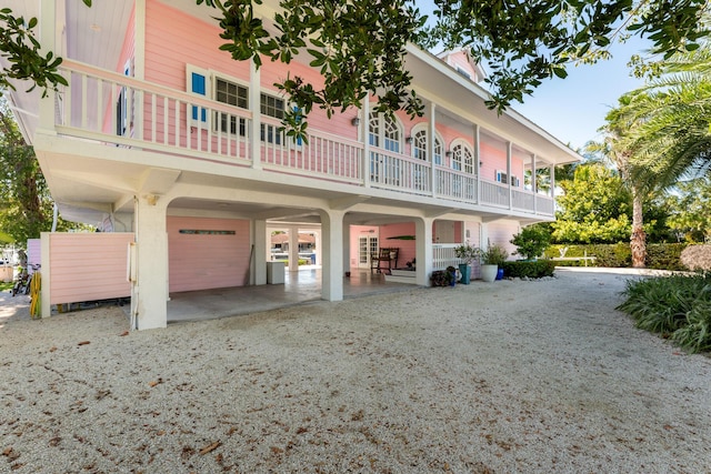 exterior space featuring an attached garage, a balcony, and gravel driveway