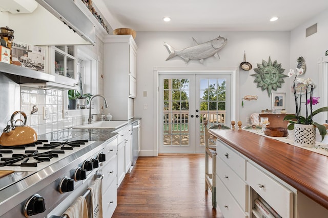 kitchen with white cabinets, stainless steel dishwasher, light wood-style floors, wooden counters, and a sink