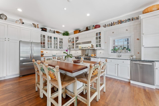 kitchen with stainless steel appliances, white cabinets, light wood-style floors, and under cabinet range hood