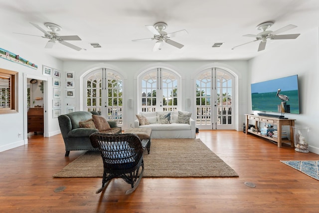 interior space featuring ceiling fan, wood finished floors, visible vents, baseboards, and french doors