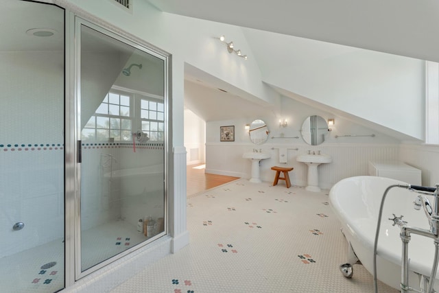 full bathroom with a stall shower, wainscoting, vaulted ceiling, a sink, and a freestanding tub