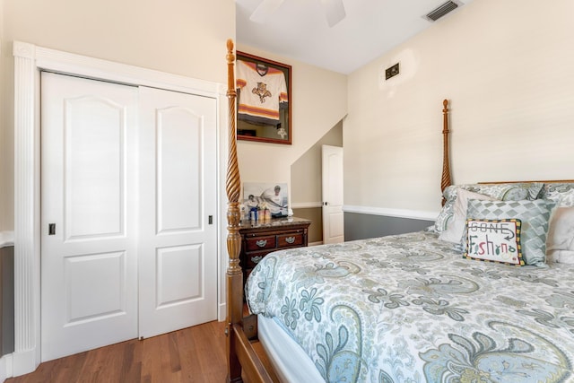 bedroom with a closet, wood finished floors, visible vents, and a ceiling fan