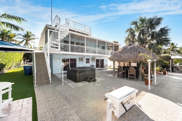 rear view of property featuring stairway, a hot tub, a gazebo, a sunroom, and a patio area