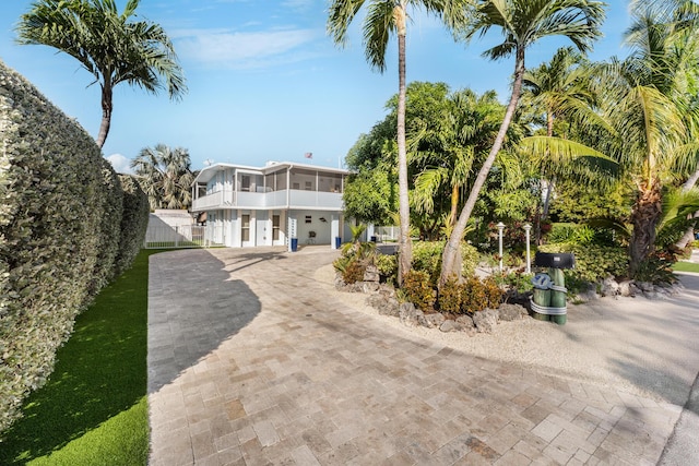 exterior space featuring decorative driveway, fence, and a sunroom