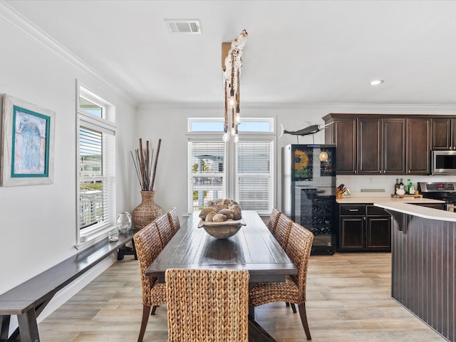 dining area featuring light wood-type flooring, crown molding, and recessed lighting