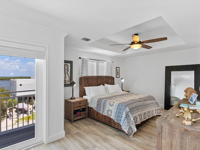 bedroom featuring a raised ceiling, access to outside, light wood-type flooring, ornamental molding, and a ceiling fan