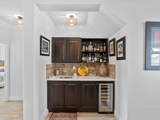 indoor wet bar with wine cooler, light wood-type flooring, baseboards, and tasteful backsplash
