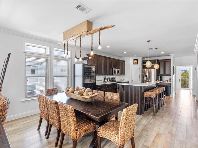 dining space with light wood-style floors, crown molding, recessed lighting, and baseboards
